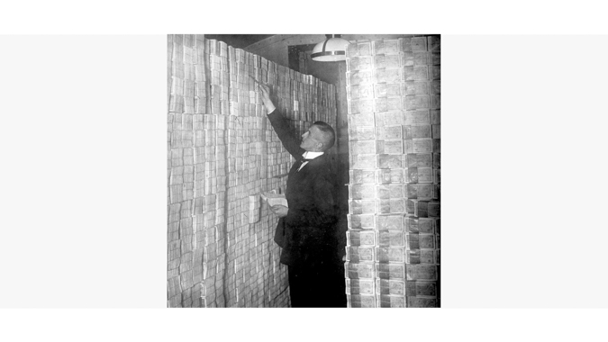 Man Between Stacks of Money Demonstrates Hyperinflation